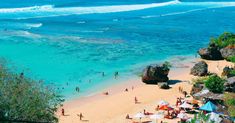 the beach is crowded with people and umbrellas near the water's edge, as seen from above