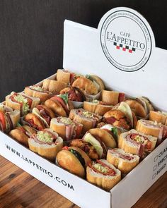 a box filled with sandwiches sitting on top of a wooden table