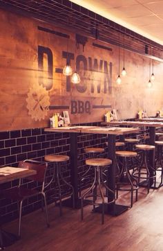 the interior of a restaurant with wooden tables and stools in front of a brick wall