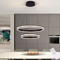 a modern dining room with an oval light fixture hanging from the ceiling and a white table surrounded by chairs