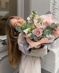 a woman holding a bouquet of flowers in front of her face and looking at the camera