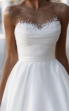 a woman wearing a white dress with beading on it