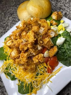 a white plate topped with salad and two buns next to each other on top of a table