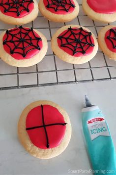 cookies decorated with spider webs and icing on a cooling rack next to a bottle of toothpaste