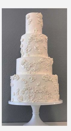 a large white wedding cake sitting on top of a table in front of a gray wall