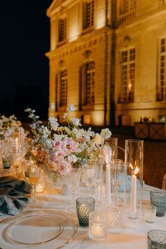 the table is set with candles, plates and flowers in vases on top of it