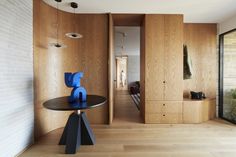 a room with wood paneling and a round table in the center, next to an open door