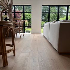 a living room filled with furniture next to large windows and lots of wood flooring