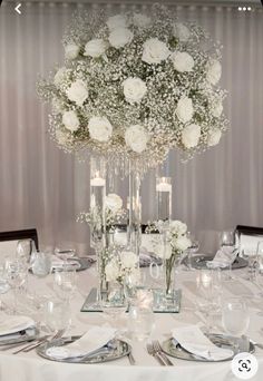 the centerpiece is surrounded by white flowers and candles for an elegant wedding table setting