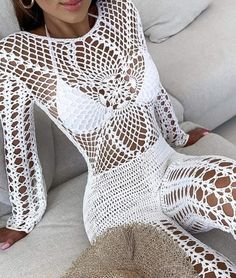 a woman is sitting on a couch wearing white crochet