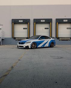 a blue and white car parked in front of some garage doors