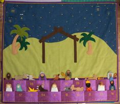 a nativity scene is displayed on a table with purple and green material, depicting the birth of jesus