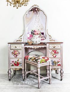 an ornate pink vanity with mirror, stool and flowered upholstered cushion on it