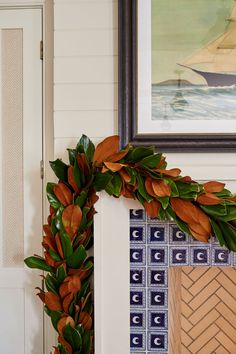 a wreath is hanging on the wall next to a door with a sailboat painted on it