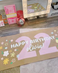 a happy birthday sign sitting on top of a floor next to a mirror and other decorations