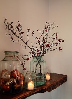 vases filled with flowers and candles sit on a shelf