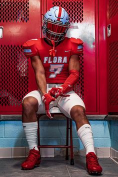 a football player is sitting in the locker room with his foot on a chair and wearing red shoes