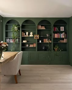 a dining room with green walls and built in bookshelves