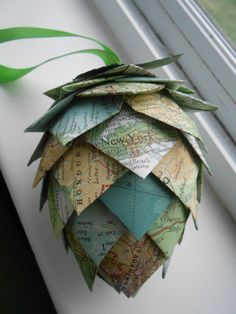 an origami pineapple hanging from a window sill with green ribbon on it