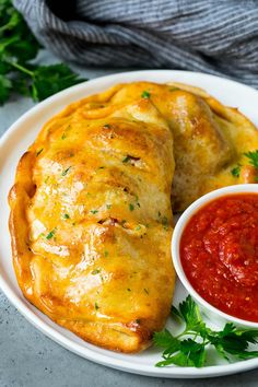 two enchiladas on a white plate with salsa and ketchup next to it