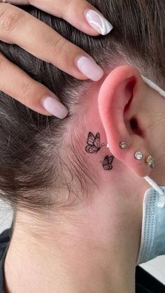 a woman's left ear has a butterfly tattoo on it