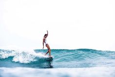 a woman riding a wave on top of a surfboard in the middle of the ocean