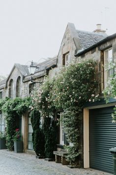 an old brick building with ivy growing on it's sides and flowers in the windows