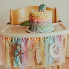 a cake on top of a wooden table with ribbons around it and a bird sitting on top of the cake