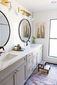 a bathroom with two sinks and mirrors on the wall next to each other in front of a window