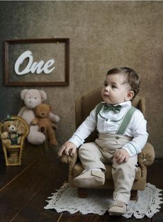 a little boy sitting in a chair next to a teddy bear