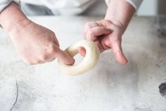 a person is holding a doughnut in their right hand and touching it with the other hand