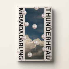 a book cover with pearls floating in the air and clouds behind it, on top of a white surface