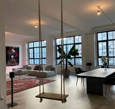 a living room filled with furniture and lots of windows next to a wooden floor covered in rugs