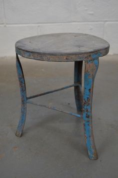 an old blue stool sitting in front of a white brick wall