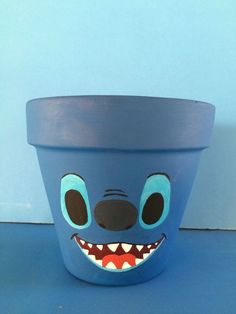 a blue planter with a face painted on it's side and teeth in the middle