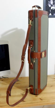 a suitcase sitting on top of a wooden table next to a computer monitor and keyboard