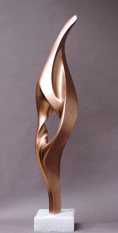 a bronze sculpture on a white pedestal with a gray wall in the backgroud