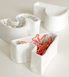 two white containers with orange and red cords in them sitting on a table next to each other