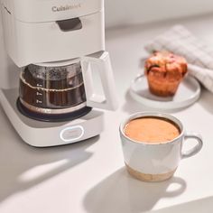 a cup of coffee next to a muffin on a plate