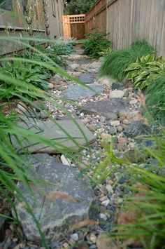 a garden with rocks and grass next to a fence