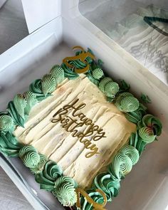 a birthday cake in a white box with green icing