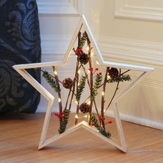 a white star shaped christmas decoration with pine cones and berries on the top, sitting on a wood floor