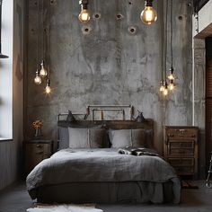 a bedroom with concrete walls and lights hanging from the ceiling