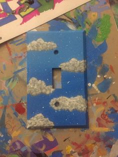 a blue light switch cover with clouds painted on it