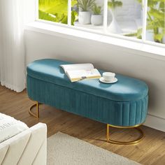 a blue bench sitting in front of a window next to a white rug on top of a hard wood floor