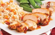 a white plate topped with meat and rice next to green beans on a red table cloth