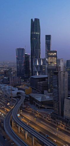 an aerial view of a city at night with traffic on the road and skyscrapers in the background