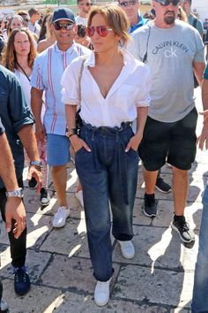 a woman in white shirt and jeans walking with other people