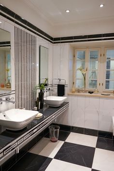 a bathroom with black and white tile flooring and two sinks in front of large mirrors