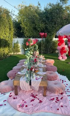 a table set up for a valentine's day party with pink and red balloons